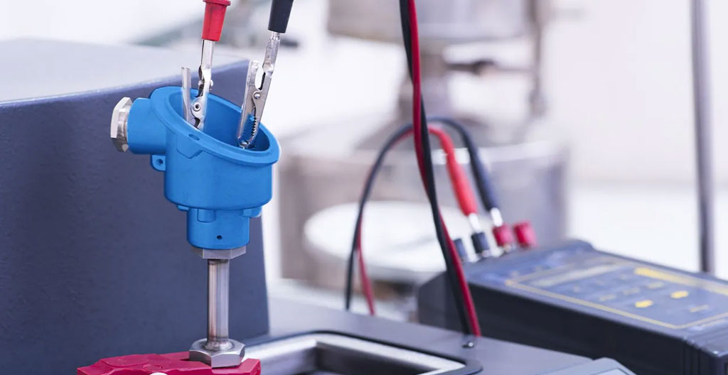 Gros plan d'une sonde de température PT100 montée sur une tuyauterie d'échangeur thermique en acier inoxydable avec câblage visible